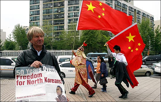 올림픽 공원 평화의 문 근처에 서 있던 북한인권 활동가 독일인 폴러첸 씨 주변으로 오성홍기를 든 중국측 축하객들이 지나고 있다.