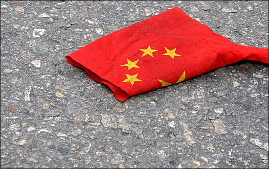 중국 축하객들이 경찰에 의해 분리되어 물러난 길바닥에 밟히고 더렵혀진 오성 홍기가 널려져 있다.