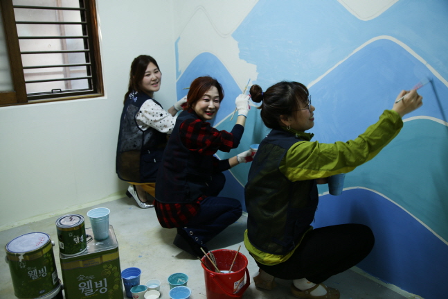 자원봉사자들이 KCC의 친환경 페인트로 벽면을 칠하며 주거환경 개선 봉사활동을 진행하고 있다.ⓒKCC