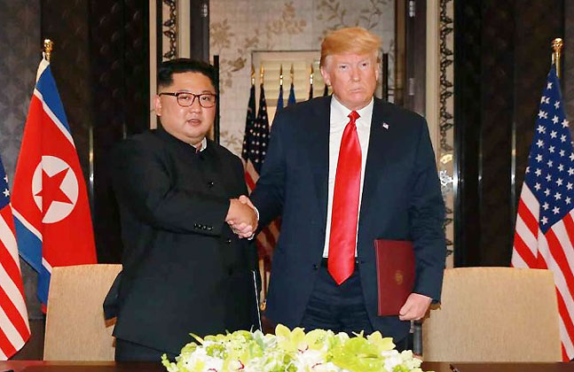 김정은 북한 국무위원장과 도널드 트럼프 미국 대통령이 12일 공동성명에 서명한 뒤 악수하고 있다.ⓒ연합뉴스