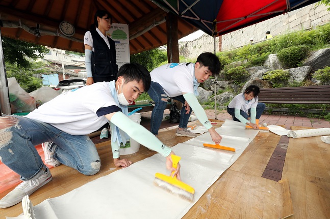 지난 13일 대우건설 대학생 홍보대사들이 서울시 성북구에 위치한 노후주택에 도배할 벽지에 풀을 바르고 있다.ⓒ대우건설