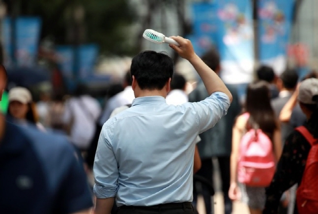 지난 24일 명동의 한 거리에서 직장인이 휴대용 선풍기와 함께 거리를 걷고 있다. ⓒ 연합뉴스 