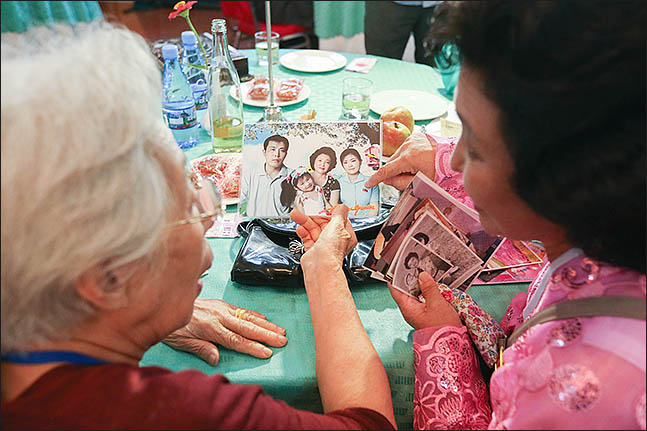 제21차 이산가족 상봉행사 첫날인 20일 오후 북한 금강산호텔에서 진행된 단체상봉에서 남측 전혜옥(90)씨와 북측 시조카 김윤경(56)씨가 가족사진을 보고있다. ⓒ사진공동취재단