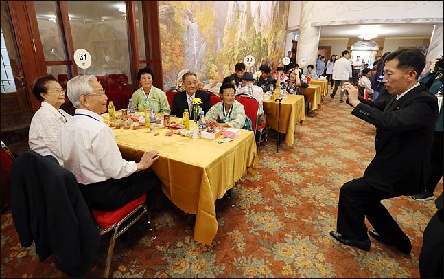 제21차 이산가족 상봉 이틀째인 21일 오후, 북한 금강산호텔에서 열린 단체상봉에서 북측의 보장성원이 남측 박갑일(79)씨 가족과 북측 처남처 문경옥(81)씨 가족의 가족사진을 촬영해주고 있다. ⓒ사진공동취재단