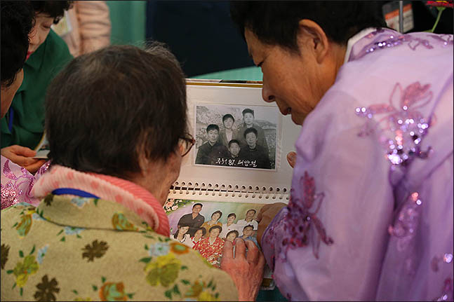 제21차 이산가족 상봉행사 첫날인 20일 오후 북한 금강산호텔에서 진행된 단체상봉에서 남측 한신자(99)씨가 북측 가족과 가족사진을 보고 있다. ⓒ사진공동취재단