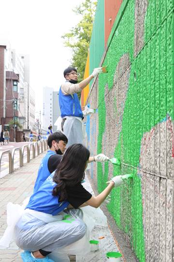 선·후배가 함께 하는 벽화 그리기 봉사활동에 참여한 멘토, 멘티들이 서울청량초등학교 담벼락에 벽화를 그리고 있다. ⓒ동아쏘시오그룹