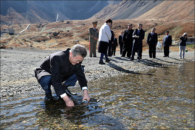 문재인 대통령이 20일 오전 김정은 국무위원장과 백두산 천지를 산책하던 중 천지 물을 물병에 담고 있다. ⓒ평양사진공동취재단