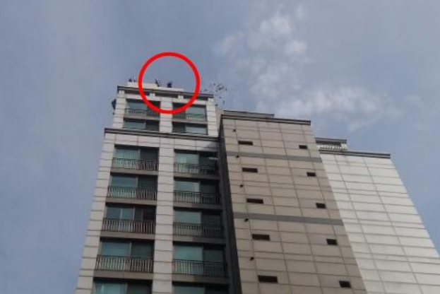 중년 남성(빨간 원 안쪽)이 26일 서울 광진구 구의동의 20층짜리 한 주상복합단지 건물 옥상에서 소동을 부리고 있다.ⓒ연합뉴스