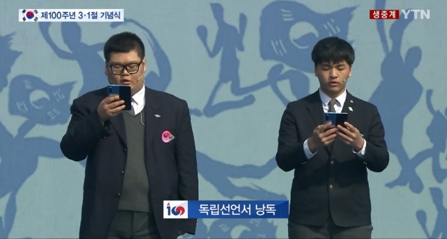 1일 서울 광화문에서 개최된 삼일절 기념식에서 독립선언서를 낭독하기 위해 연단에 오른 고등학생들이 삼성전자 폴더블폰 '갤럭시폴드'를 보면서 독립선언서를 작성한 민족대표 33인의 이름을 차례로 낭독하고 있다. YTN뉴스 영상 캡쳐