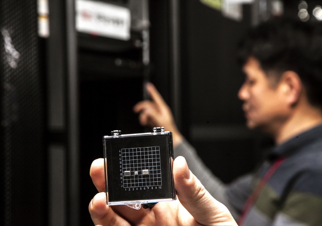 SK텔레콤 직원이 가입자 인증서버에 적용된 양자난수생성 칩을 들고 있다. ⓒ SKT
