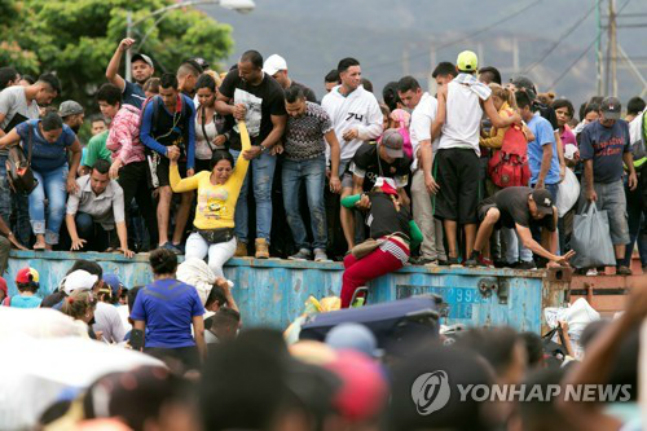 베네수엘라 국민들이 3일(한국시각) 타치라 강 위의 시몬 볼리바르 대교를 봉쇄한 컨테이너를 넘어 콜롬비아로 탈출하고 있다. ⓒ연합뉴스