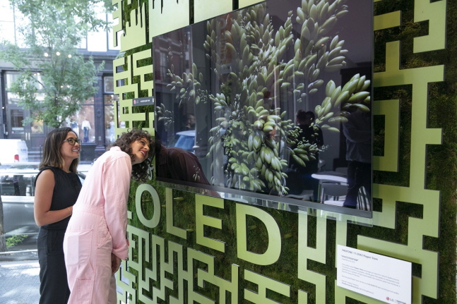 LG전자가 12일(현지시간)부터 14일까지 미국 뉴욕 맨해튼에서 운영한 '카페 올레드'에서 아미라 카셈 셰프(오른쪽) 등이 팬톤사가 선정한 올해의 여름 컬러 '페퍼 스템' 조형물 앞 LG 올레드 TV를 살펴보고 있다.ⓒLG전자