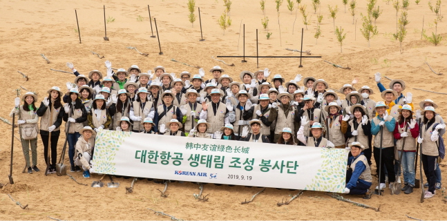 대한항공 직원들이 18일(현지시간) 중국 네이멍구 쿠부치 사막의 조림지 ‘대한항공 생태원’에서 진행된 나무심기 봉사활동에 참가한 뒤 기념촬영을 하고 있다.ⓒ대한항공
