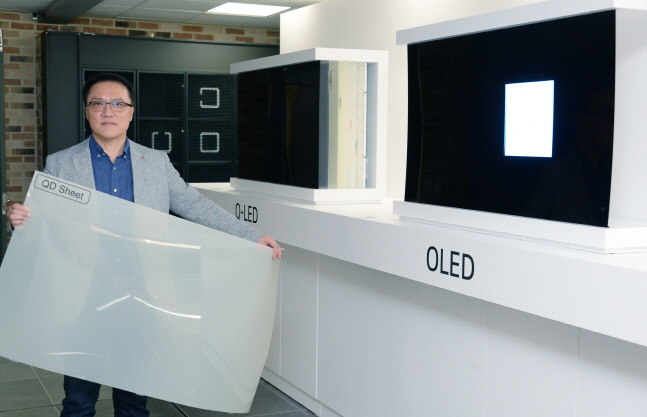 남호준 LG전자 홈엔터테인먼트(HE)연구소장(전무)이 지난 17일 서울 여의도 트윈타워에서 개최된 '8K 및 올레드 기술설명회'에서 패널의 차이를 설명하기 위해 국내시장에 판매중인 QLED TV에 적용된 퀀텀닷 시트를 들어 보이고 있다.ⓒLG전자