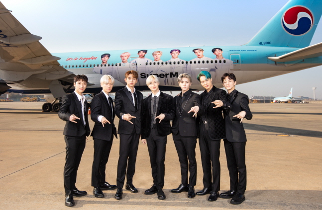 슈퍼엠 멤버들이 자신들의 사진으로 래핑한 대한항공 항공기 앞에서 기념 촬영을 하고 있다.ⓒ대한항공