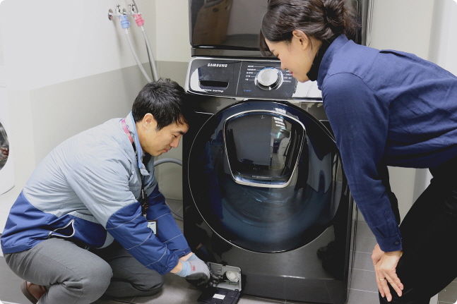 삼성전자서비스 수리 엔지니어가 출장 점검 서비스를 신청한 고객에게 플러스 원 케어 서비스의 일환으로 드럼세탁기 배수펌프 잔수 제거 방법을 설명하고 있다.ⓒ삼성전자서비스