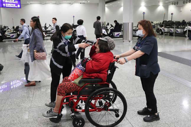 홍콩 공항에서 지난 23일 한 보건 당국자가 한 승객의 체온을 재고 있다. 홍콩에서 우한발 폐렴에 감염된 두번째 확진자가 나오면서 당국이 방역을 강화하고 있다.ⓒAP/뉴시스