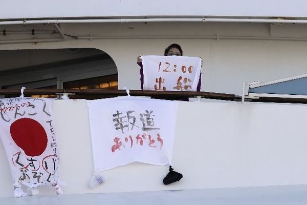 11일 일본 요코하마항에 정박해 있는 유람선 '다이아몬드 프린세스'호에서 한 여성이 출항 시간을 쓴 천을 들고 있다. ⓒ뉴시스