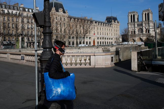 22일(현지시간) 마스크를 쓴 한 남성이 프랑스 파리의 인적 없는 노트르담 대성당 주변을 걷고 있다.ⓒ뉴시스