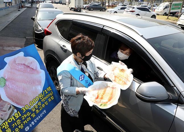 서울 강서수산시장에 설치된 드라이브 스루 판매소에서 직원이 차 안의 고객에게 광어회를 건네고 있다. ⓒ수협