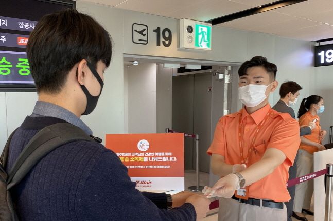 제주항공 직원들이 김포공항 탑승구에서 탑승객들에게 손소독제를 나눠주고 있다.ⓒ제주항공