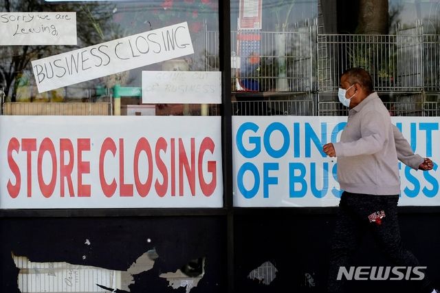 사진은 지난 21일 신종 코로나바이러스 감염증(코로나19)로 문을 닫은 일리노이주 나일스 지역의 한 가게를 지나는 남성의 모습. ⓒ나일스=AP
