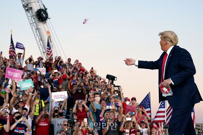 도널드 트럼프 미국 대통령이 지난 12일(현지시각) 미 플로리다주 샌퍼드의 올랜도 샌퍼드 국제공항에 선거 유세차 도착해 지지자들을 향해 마스크를 던져 주고 있다. ⓒAP/뉴시스
