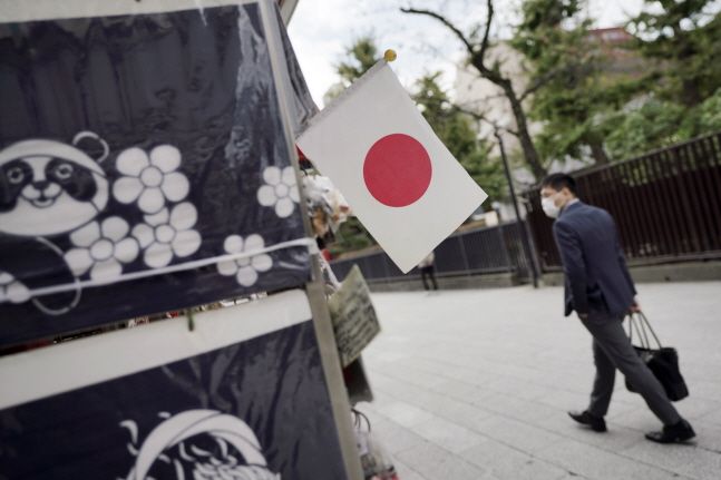 일본 도쿄 아사쿠사 지구에서 마스크를 쓴 한 남성이 일장기가 걸린 한 상점 앞을 지나고 있다.ⓒ뉴시스