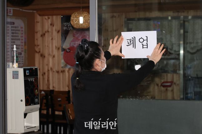 서울 동작구에서 식당을 운영하는 한 업주가 식당 문에 폐업이 적힌 종이를 붙이고 있다.ⓒ데일리안 류영주 기자