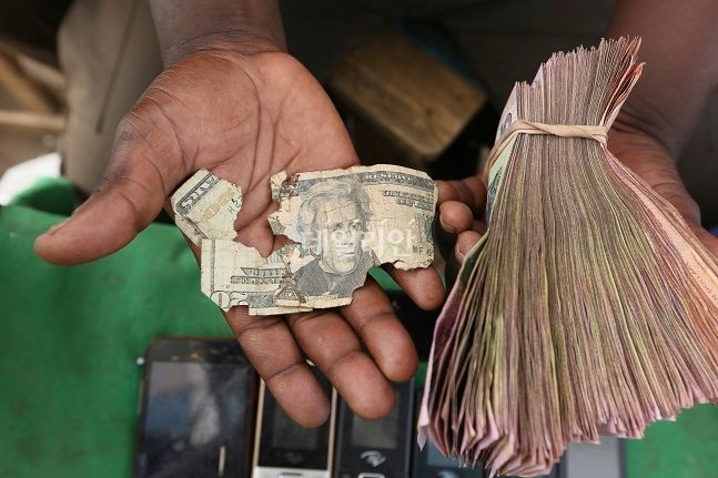 지난해 10월21일(현지시간) 짐바브웨 하라레의 한 시장에서 화폐 거래상이 낡고 닳은 미화 20달러짜리 들고 있다. 짐바브웨는 하이퍼인플레이션으로 미국 달러 가치가 매우 높아 낡은 미국 달러를 수선해서 사용하기도 한다. ⓒ뉴시스
