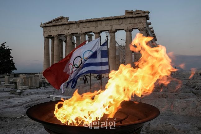 지난 10월 베이징 동계 올림픽을 위해 점화된 성화가 그리스 아테네의 아크로폴리스 언덕 꼭대기에 있는 고대 파르테논 신전 앞에서 타오르고 있다. ⓒAP/뉴시스