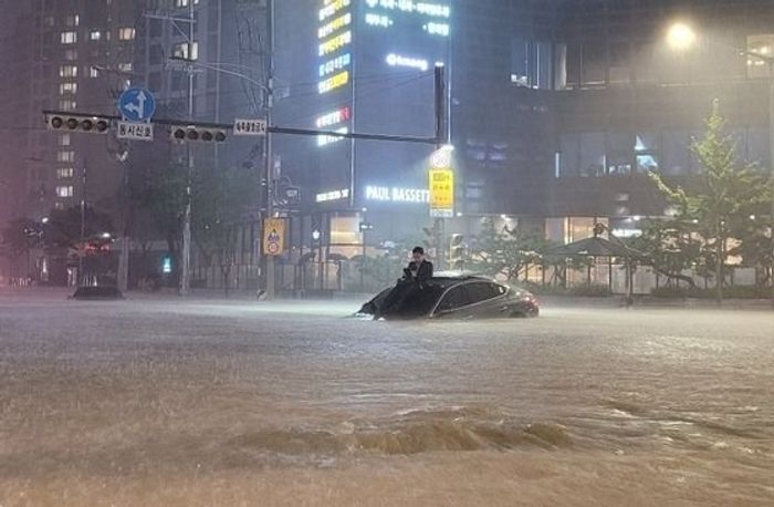 중부지방에 80년 만에 기록적인 폭우가 내린 8일 저녁 한 남성이 서울 서초동에서 침수된 차량 위로 올라가 몸을 피하고 있다. 온라인 커뮤니티 캡처