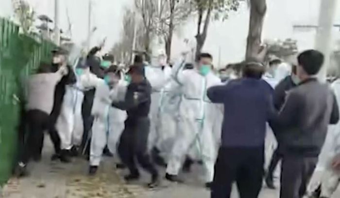 지난 23일 중국 허난성 정저우의 대만 폭스콘 공장에서 노동자들과 방호복을 입은 보안요원들이 뒤엉켜 격렬한 몸싸움을 벌이고 있다. ⓒ AP/뉴시스