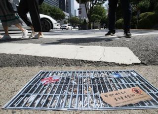 담배꽁초 가득한 배수구 포스터 지나는 시민들